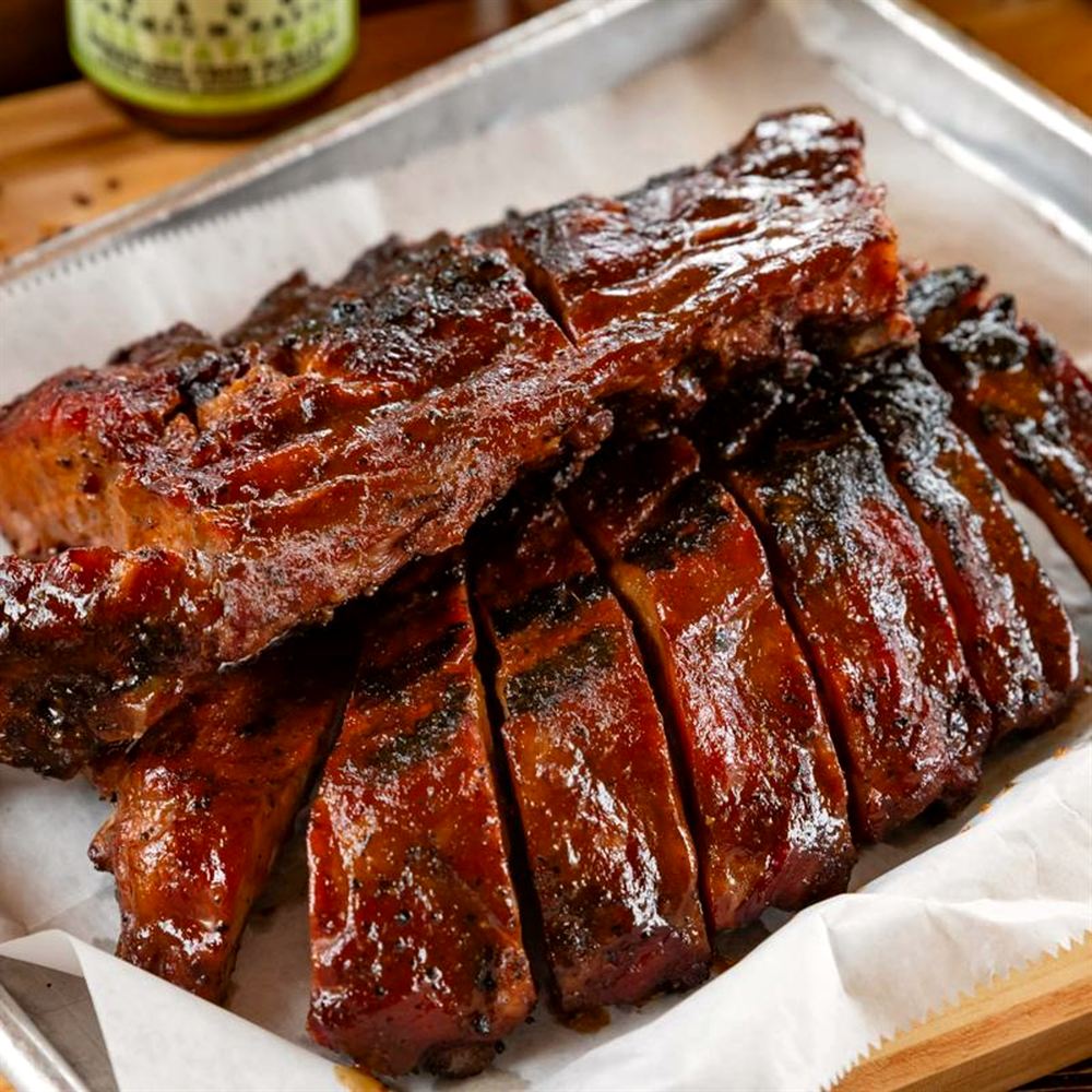 Glazed baby back ribs, sliced and stacked on a tray